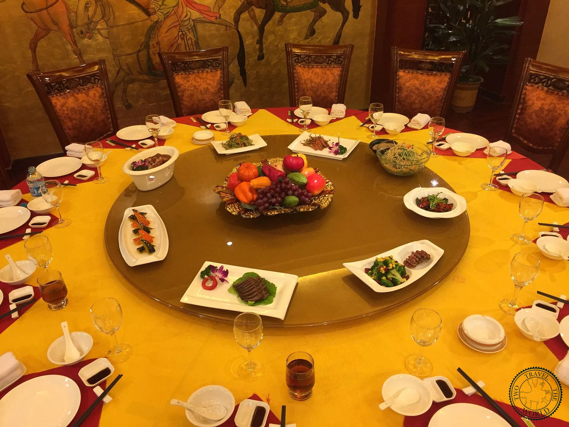 Chinese banquet table set with dishes on a lazy susan, chopsticks, and fruit centerpiece