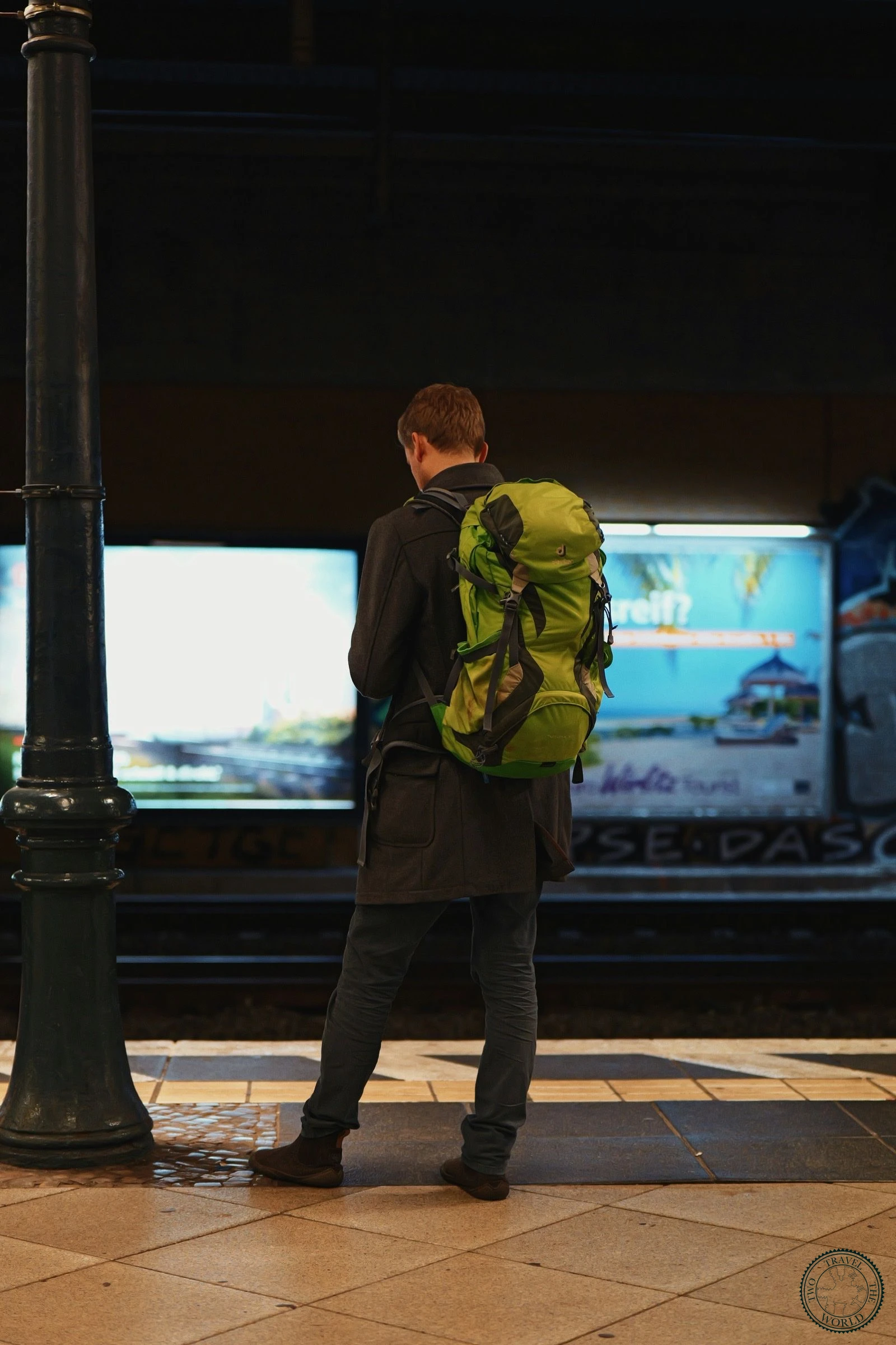 Backpacker with a green rucksack waiting at a train station platform