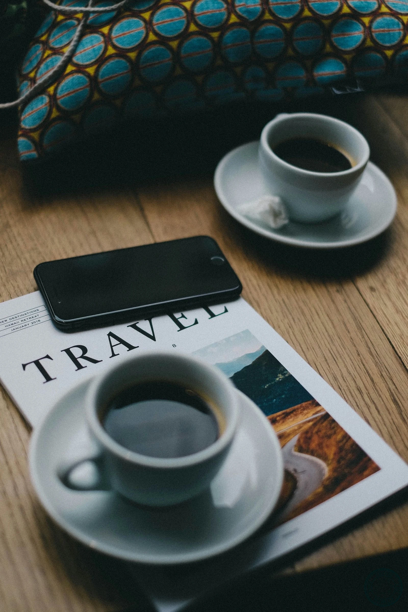 Smartphone and coffee cups on a travel magazine, planning the next trip