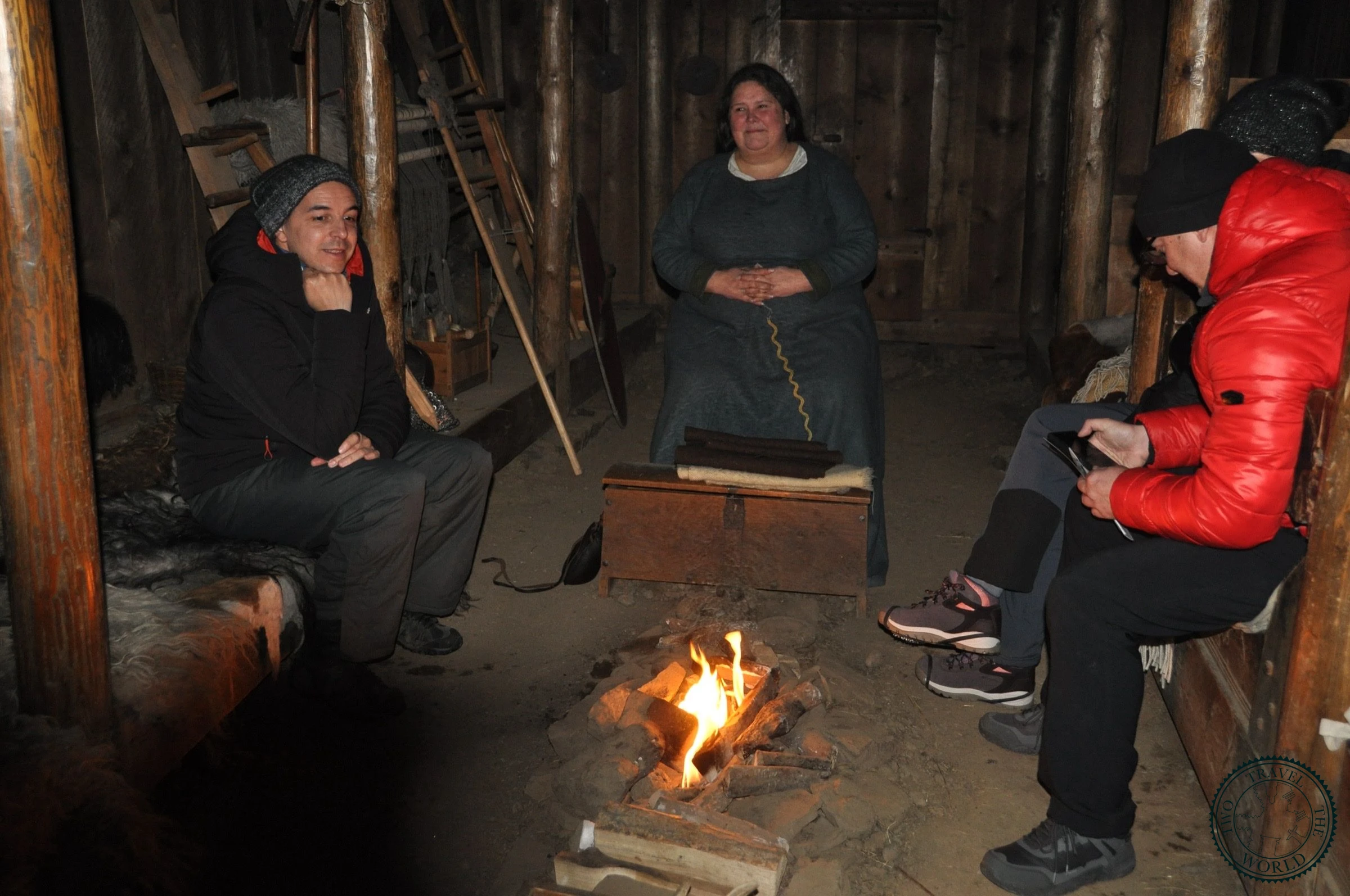 Visitors seated around the central fire while a guide in Viking-era dress tells the sagas