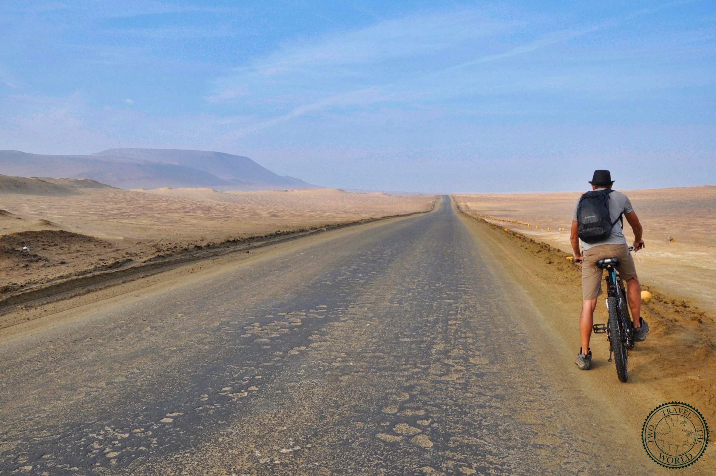 Two cyclists riding through the desert landscape of Paracas National Reserve at sunrise