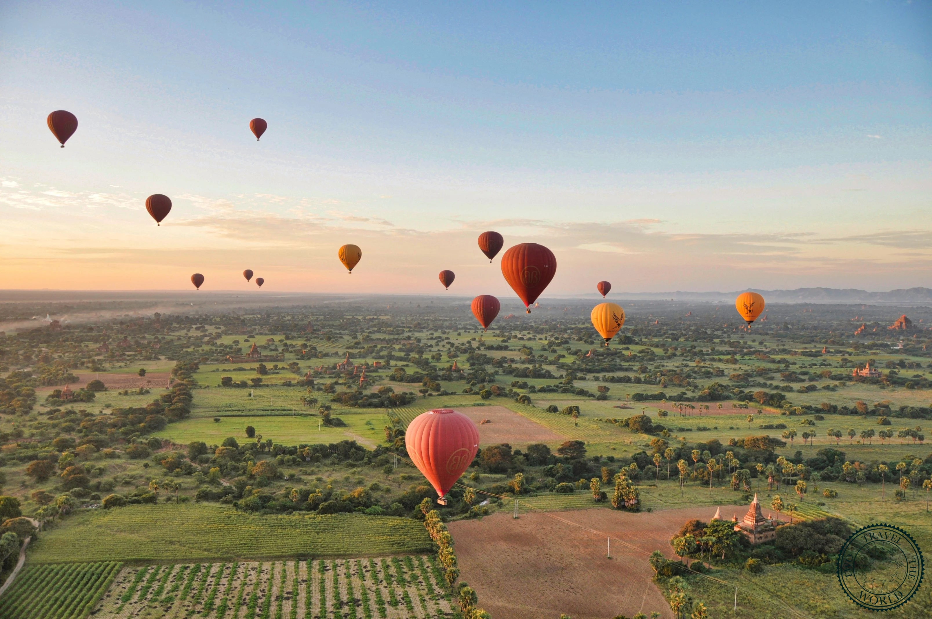 Multiple hot air balloons inflating at dawn over Bagan temples