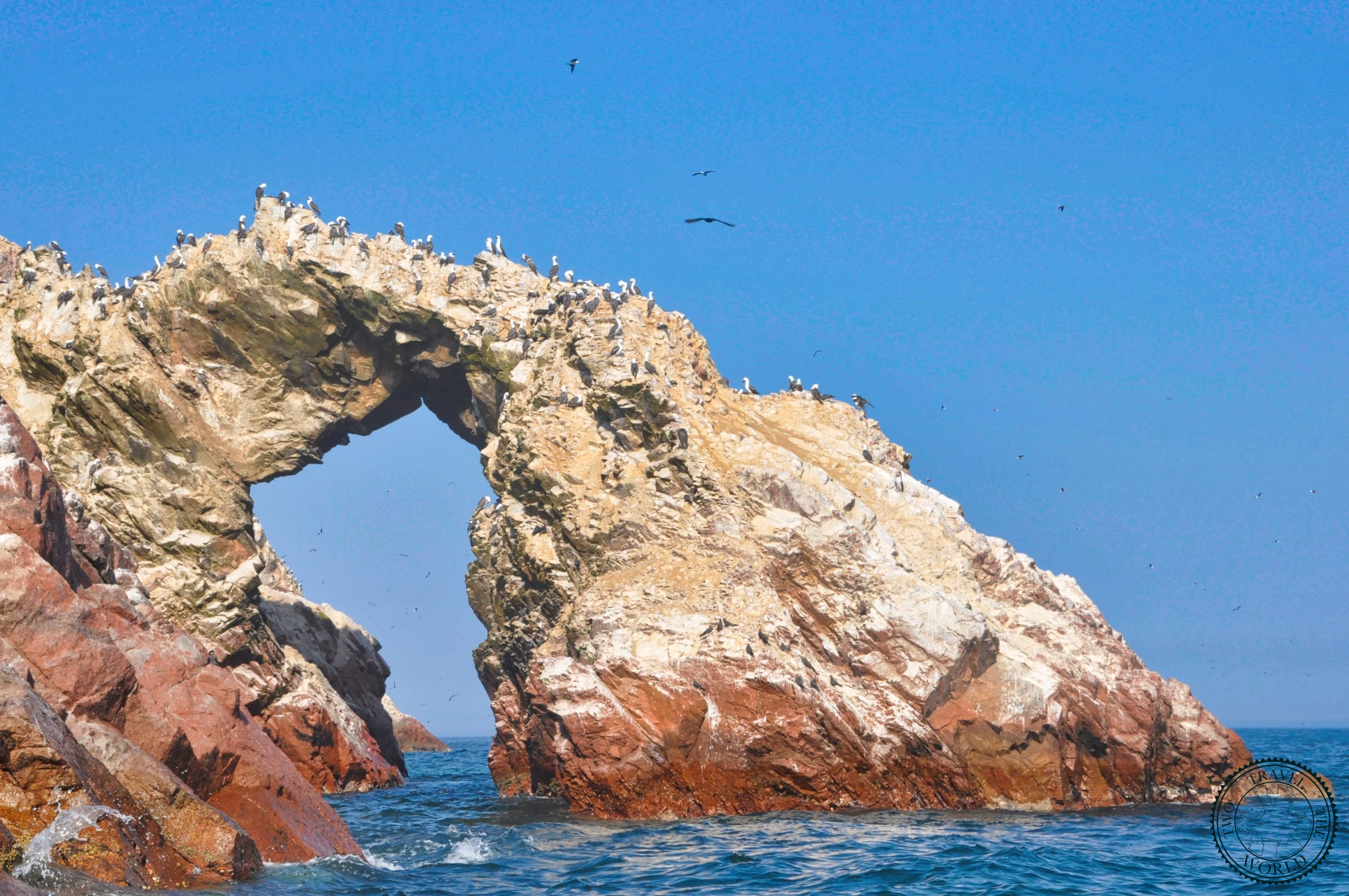 Rocky Ballestas Islands archipelago rising from the Pacific Ocean covered in white guano deposits