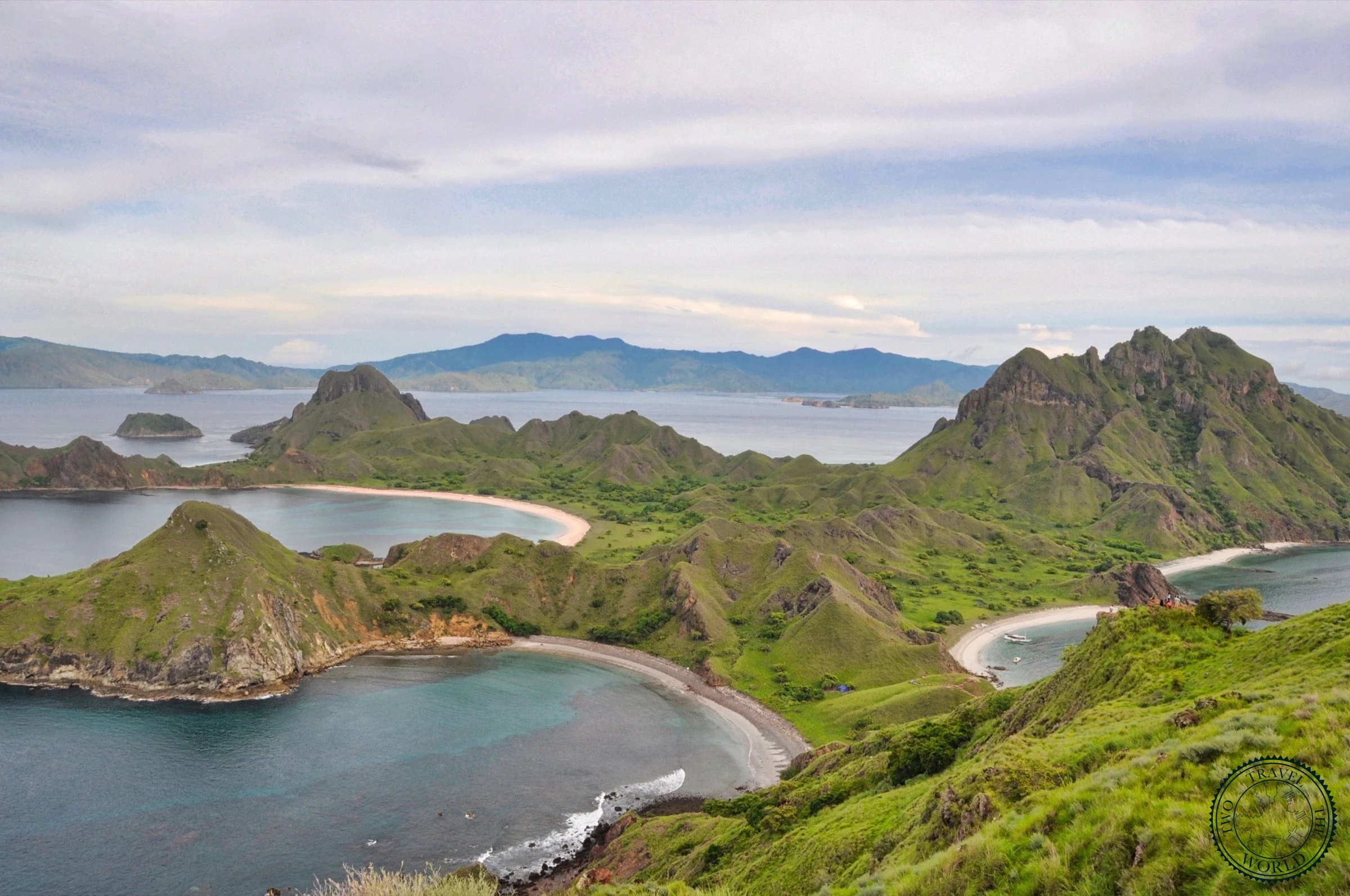 Panoramic view from Padar Island summit showing three crescent bays with turquoise waters